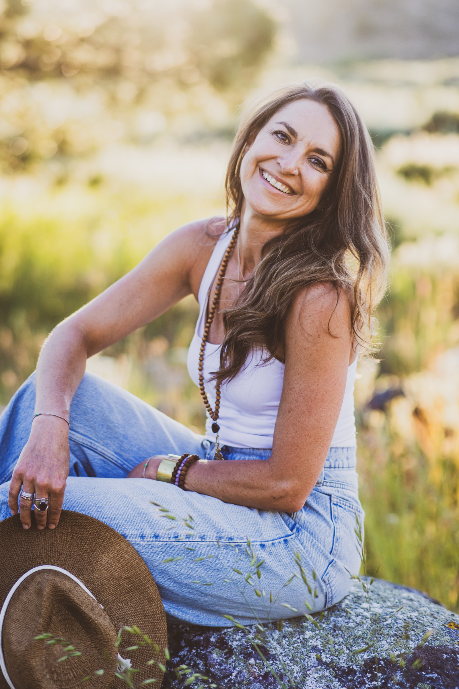 Kaila Leilani by the river at golden hour, holding her mala beads at her heart